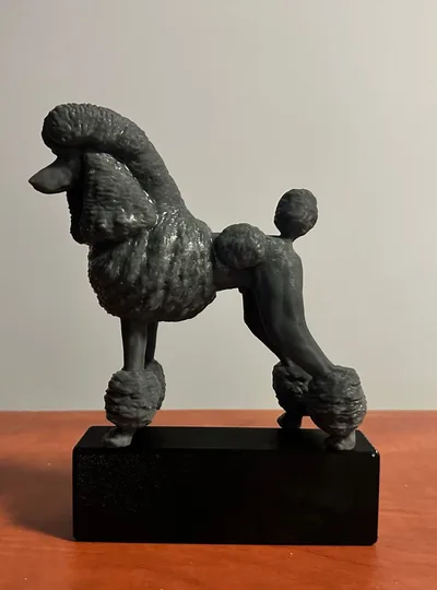 Ciemna statuetka pudla na czarnej podstawie