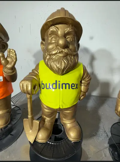 Złota figurka krasnala w żółtym stroju z napisem Budimex